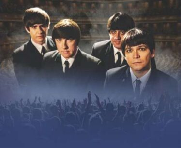 Four men in suits with Beatles-style haircuts stand in front of a concert hall background, with a crowd and raised hands in the foreground.
