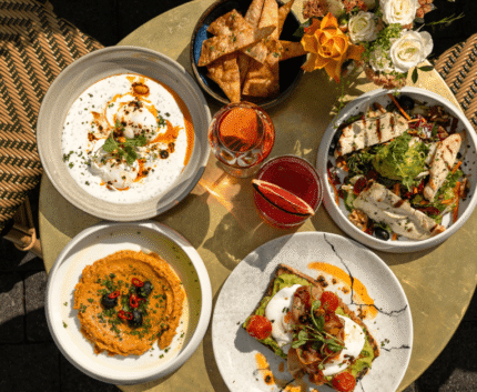 Vibrant brunch spread on an outdoor terrace with fresh salads, artisan bread, and vibrant cocktails under sunny skies.