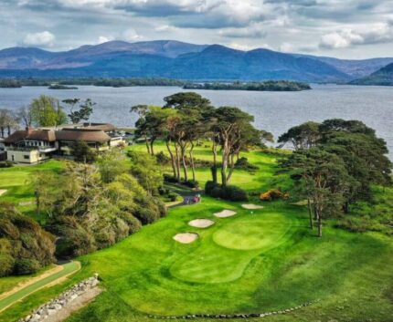 Scenic view of lush golf course with mountains and lake, offering serene relaxation and picturesque landscapes.