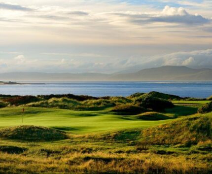 Stunning seaside golf course with lush greenery and ocean views, perfect for a relaxing stay with leisure activities.