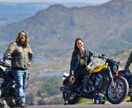 Guests enjoying a scenic mountain view on motorbikes, surrounded by lush landscapes, ideal for adventurous travellers.