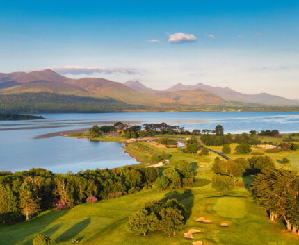 Scenic lakefront with lush golf courses and mountain views at luxury hotel resort, perfect for a relaxing getaway.