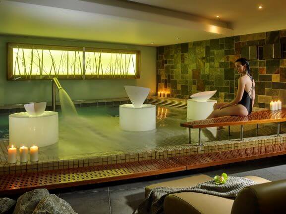 Relaxing indoor spa with candles, serene pool, and modern seating at luxury hotel.