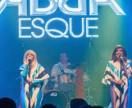 Live ABBA tribute show at hotel theatre, vibrant stage lights, musical evening entertainment for guests.