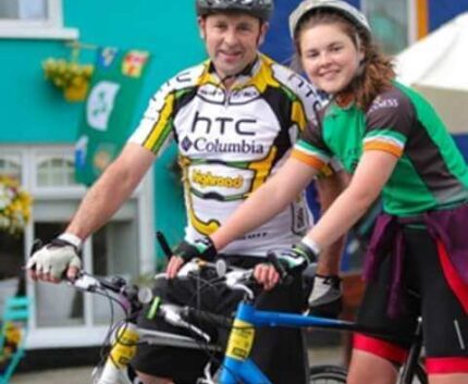 Guests enjoying cycling in vibrant town near charming hotel, featuring colourful buildings and bike-friendly amenities.