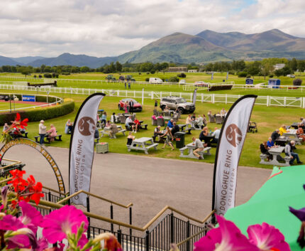 Picturesque hotel garden with dining, racecourse views, and mountain backdrop, providing a tranquil escape.