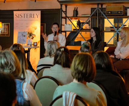 Stylish hotel event space with speakers, warm lighting, elegant seating, and attentive guests.