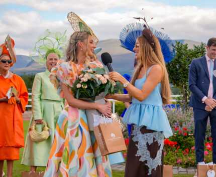 Guests enjoying outdoor fashion event with vibrant dresses and scenic views at luxury hotel garden.