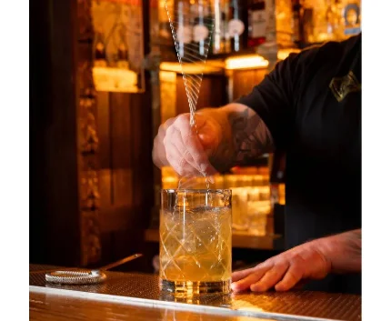 Bartender crafting a cocktail at an elegant hotel bar with warm lighting and a selection of premium spirits.