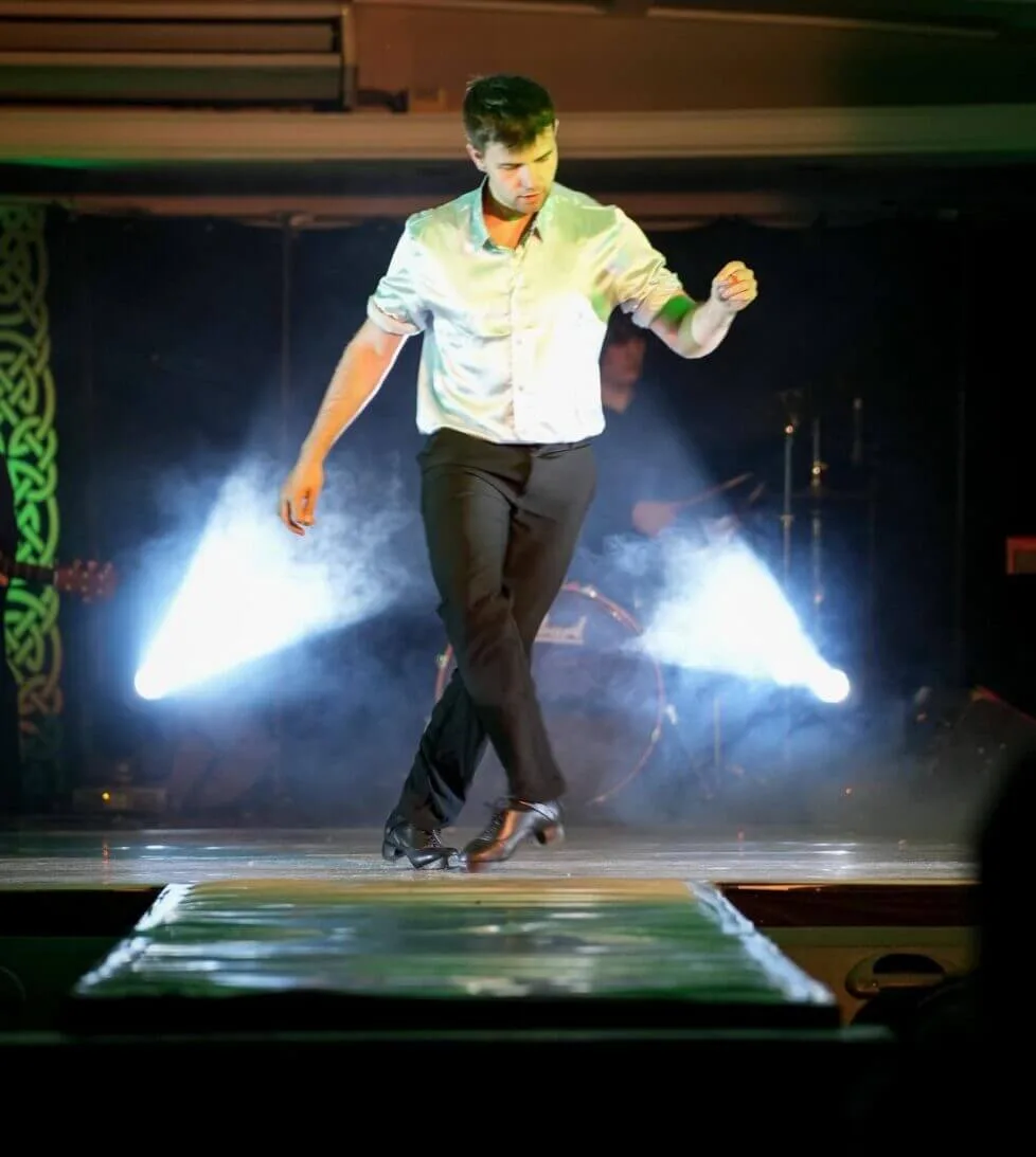 Dancer performing on stage with spotlight and fog at hotel entertainment show, creating a lively, engaging atmosphere.